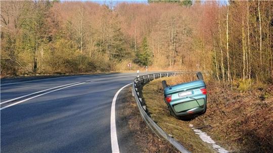 Ein grünes Auto liegt im Graben auf dem Dach.