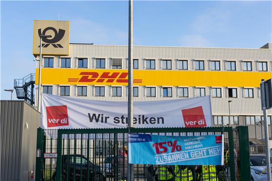 Ein Banner mit der Aufschrift „Wir streiken“ der Gewerkschaft Ver.di hängt vor einem Gebäude des Paketdienstleisters DHL. Die Gewerkschaft Verdi hat Beschäftigte in allen Brief- und Paketzentren aufgerufen, die Arbeit niederzulegen. Foto: picture alliance/dpa | Philipp von Ditfurth