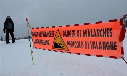 Ein Banner weist auf hohe Lawinengefahr in den Alpen hin.