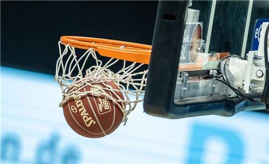 Ein Basketball landet im Korb.