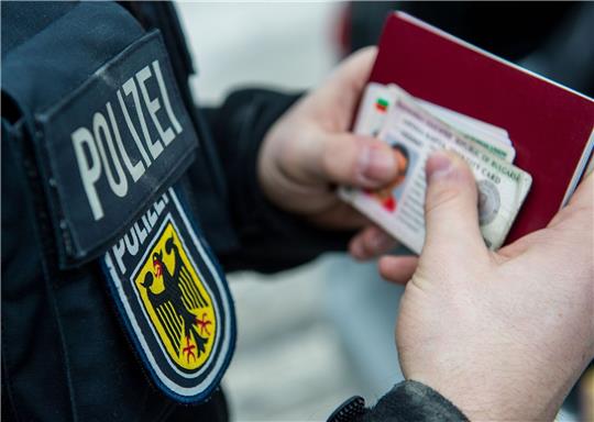 Ein Beamter der Bundespolizei hält bei einer Kontrolle ausländische Ausweise in den Händen.