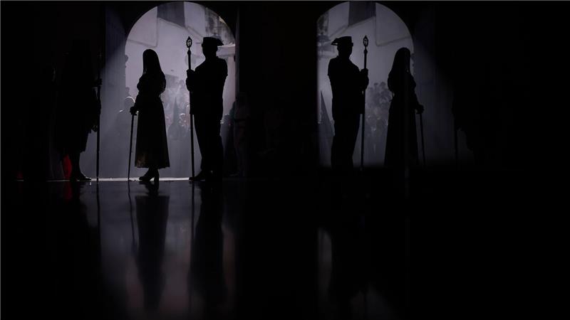 Ein Beamter der Guardia Civil (r) und ein Büßer nehmen an einer Prozession teil.