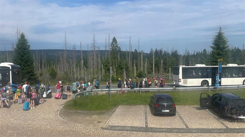 Das Foto zeigt viele Jugendliche, die in zwei unterschiedlichen Bussen einsteigen.