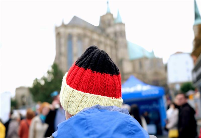 Krieg und Krisen bestimmten Einheitsfeier in Erfurt Ein Besucher des Bürgerfestes zum Tag der Deutschen Einheit trägt auf dem Domplatz eine schwarz-rot-goldene Mütze.