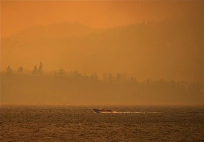 Menschenleere Städte: Kanada kämpft gegen Feuer Ein Boot fährt auf dem Okanagan-See, während der Rauch des McDougall-Creek-Wildfeuers über dem Gebiet liegt.