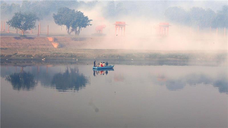 Ein Boot fährt bei Nebel auf dem Yamuna-Fluss.