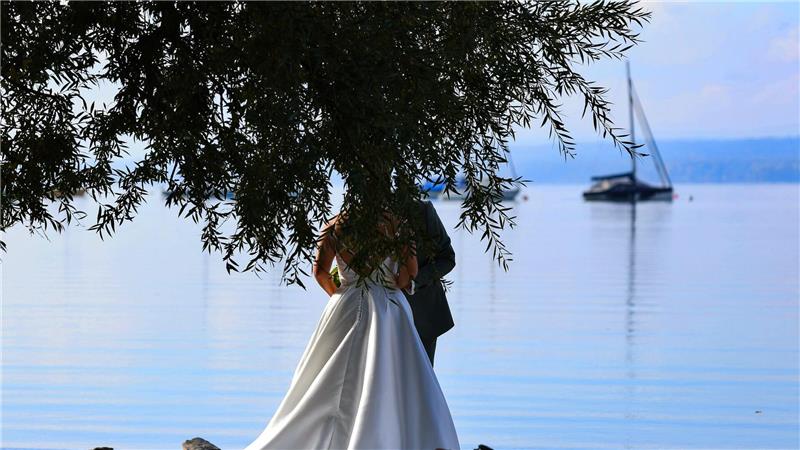 Ein Brautpaar lässt sich am Ufer des Ammersees fotografieren.