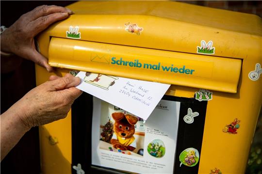 Ein Brief, den ein Kind für den Osterhasen geschrieben hat, wird in einen Briefkasten geworfen.