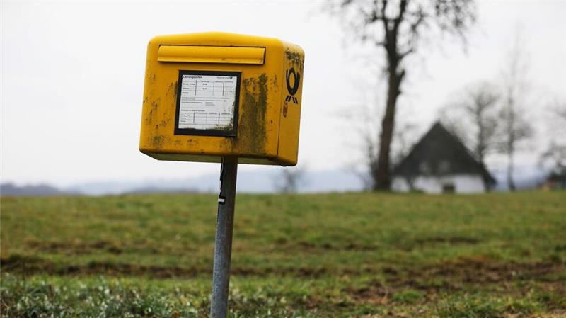 Zahl der Post-Beschwerden steigt Ein Briefkasten der Deutschen Post steht auf einer Wiese am Rand einer Siedlung im Bergischen Land (NRW).