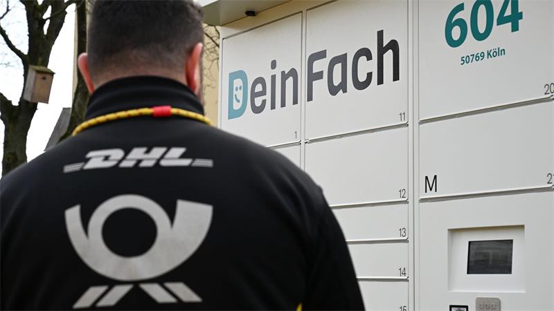 Ein DHL-Paketbote holt Sendungen aus einem DeinFach-Automaten.