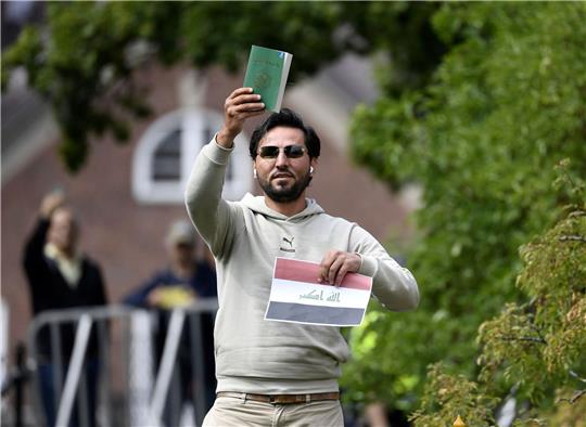 Ein Demonstrant hält eine Kopie des Korans hoch, die er mutmaßlich gemeinsam mit einer irakischen Fahne verbrennen will.