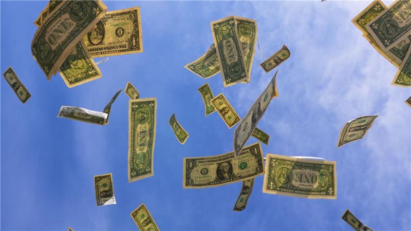 Ein-Dollar-Scheine aus den USA fallen mit dem Himmel im Hintegrund in Dallas.