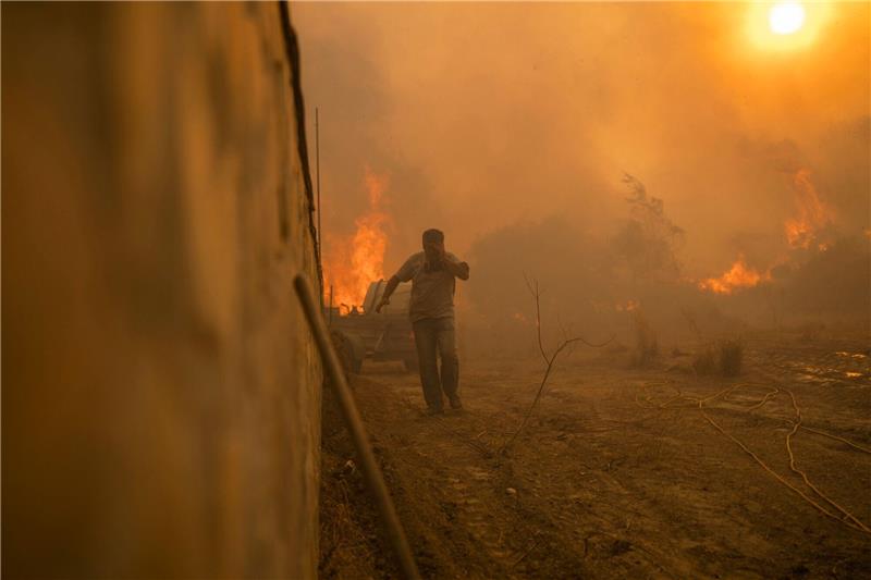 Griechische Feuerwehr: Brände größtenteils unter Kontrolle Ein Einheimischer flieht vor den Flammen von einem Waldbrand im Dorf Gennadi auf der griechischen Insel Rhodos.