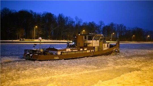 Ein Eisbrecher dreht am frühen Morgen auf dem vereisten Mittellandkanal vor der Schleuse Anderten Runden.