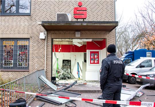 Ein Ermittler der Polizei steht vor einer Bankfiliale mit einem gesprengten Geldautomaten. In der Region Braunschweig gab es in diesem Jahr 20 solcher Fälle. Foto: Daniel Bockwoldt/dpa