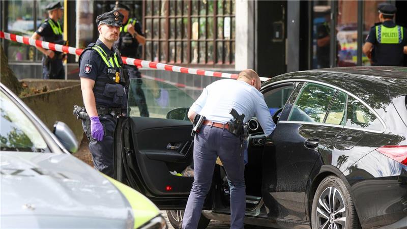 Ein Ermittler durchsucht ein abgestelltes Fahrzeug vor einer Shisha-Bar in Hamburg, in der am Morgen eine tote Person gefunden wurde.
