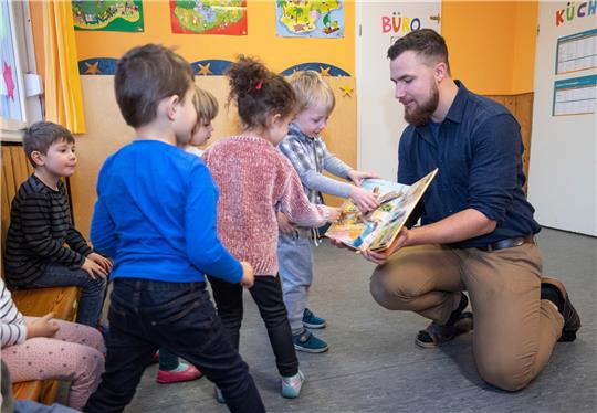 Ein Erzieher im Kindergarten bespricht mit Kindern zur musikalischen Früherziehung ein Buch über Zootiere. Symbolbild: picture alliance/dpa | Bernd Thissen