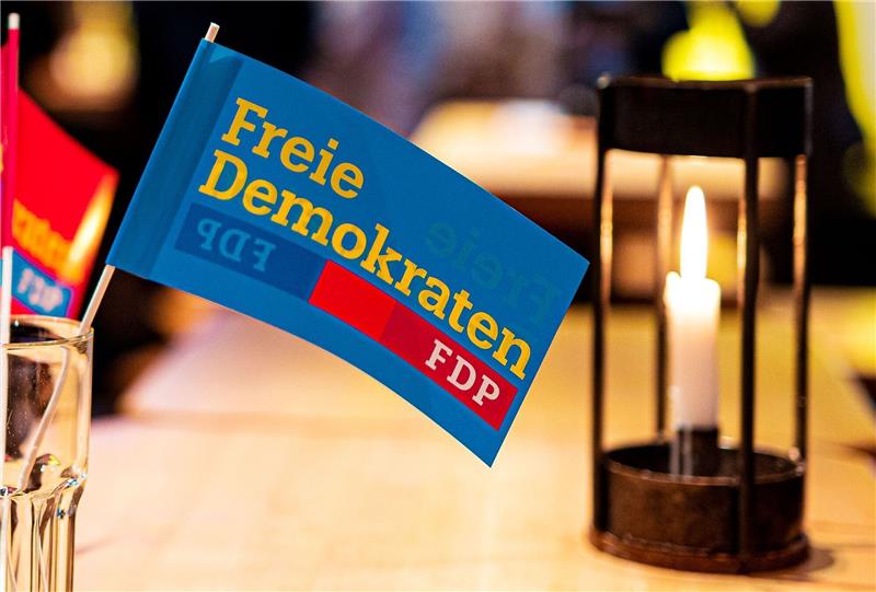 Ein Fähnchen mit der Aufschrift «Freie Demokraten FDP» steht neben einer Kerze auf einem Tisch.