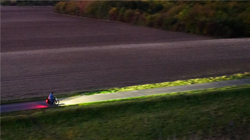Bilder des Tages Ein Fahrradfahrer fährt am frühen Morgen mit Licht über einen Feldweg bei Hannover.