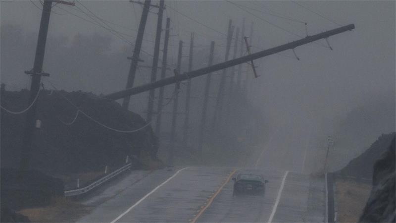 Ein Fahrzeug fährt in der Nähe von Ocean View auf Hawaii während des Hurrikans „Lala“ an einem umgestürzten Strommast vorbei, der über dem Mamalahoa Highway hängt.