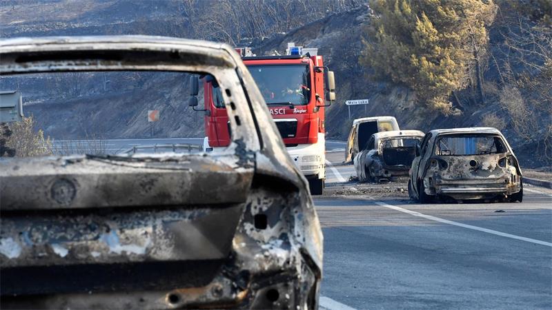 Ein Feuerwehrfahrzeug fährt nach einem Waldbrand an der kroatischen Adria zwischen ausgebrannten Autos hindurch.