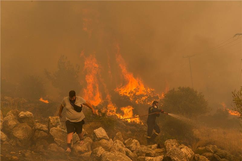 Das Jahr der Klimarekorde: Extrem ist das neue Normal Ein Feuerwehrmann kämpft am im Dorf Hasia in der Nähe von Athen gegen einen Waldbrand.