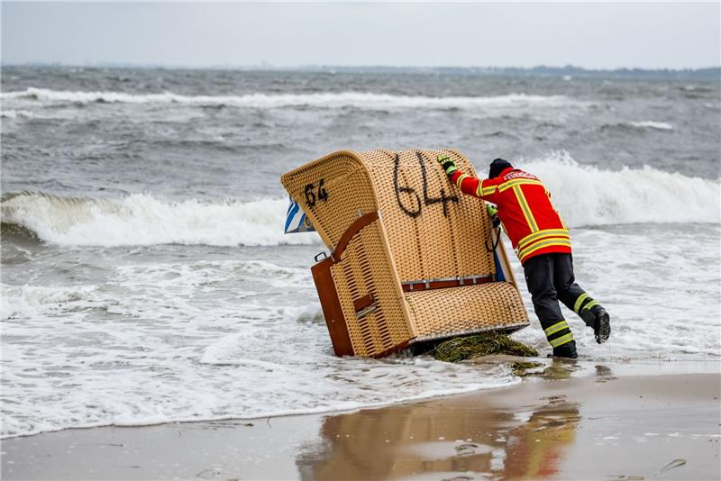 Schwere Sturmflut setzt der Ostsee-Küste zu - Eine Tote Ein Feuerwehrmann versucht, in Kiel-Schiksee einen Strandkorb vor den Flutwellen der Ostsee zu sichern.