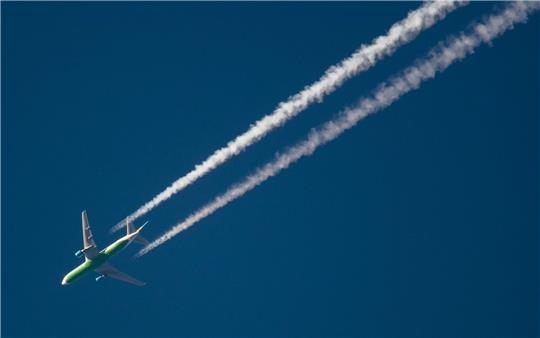 Ein Flugzeug hinterlässt Kondensstreifen am Himmel. Spätestens Mitte des Jahrhunderts soll schließlich mit grünem Wasserstoff geflogen werden.