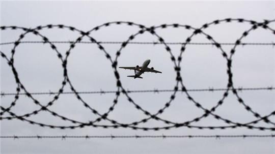 Ein Flugzeug startet am Flughafen Hannover - fotografiert durch Stacheldraht am Flughafenzaun.