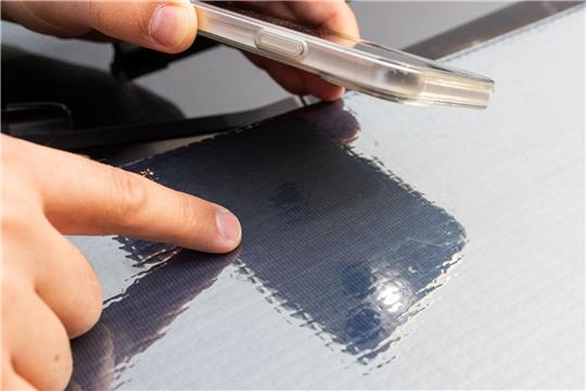 Ein Forscher des Fraunhofer ISE zeigt auf die Struktur der Solarzellen auf einer Motorhaube.
