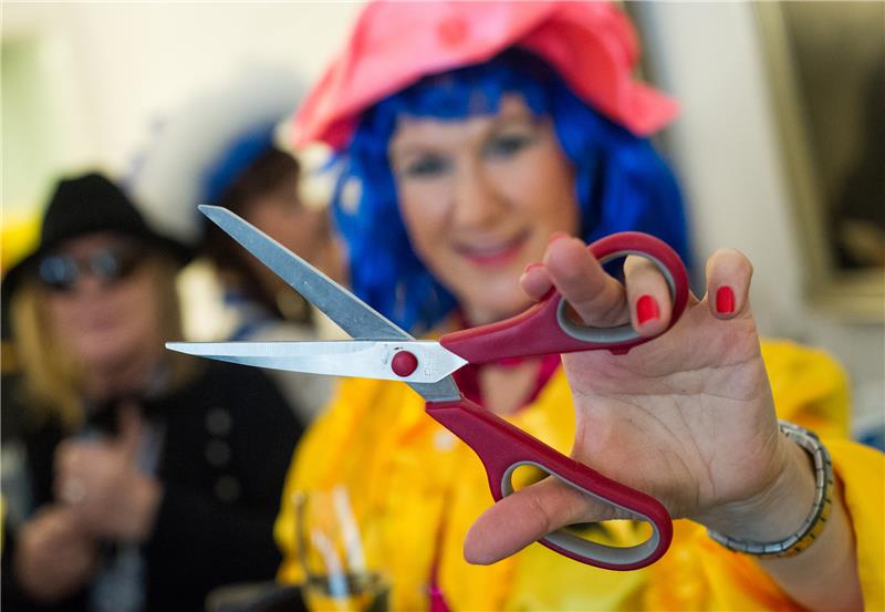 Ein Funkenmariechen hält in Hannover zur Weiberfastnacht eine Schere in der Hand. Foto: Ole Spata/dpa/Archiv.