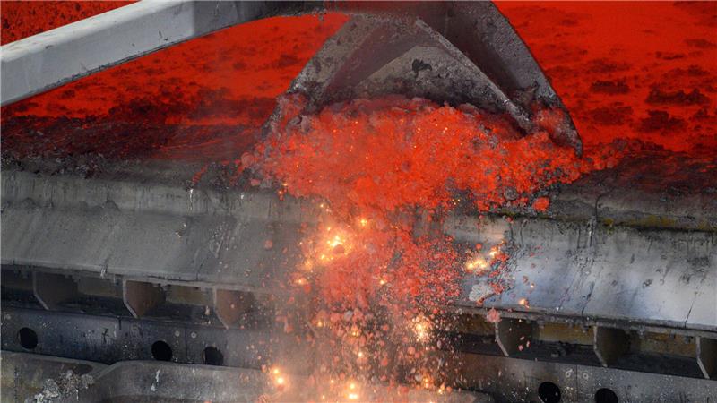 Der Greifarm eines Gabelstaplers kratzt Reste von glühendem Aluminium aus dem Schmelzofen der Firma Novelis.