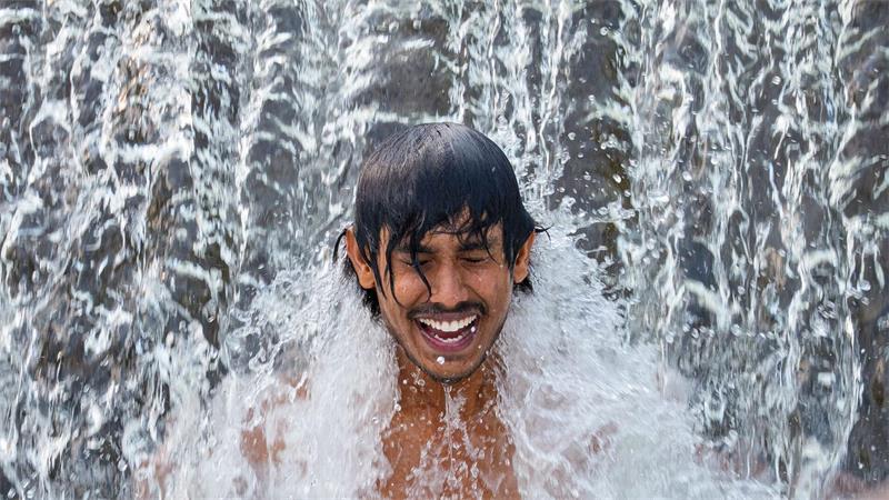 Ein Gastarbeiter aus Sri Lanka kühlt sich an einem glühend heißen Tag in einer Wasserkaskade eines Flusses außerhalb der Stadt Bragadiru in Rumänien ab.