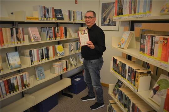 Ein Genre, das im vergangenen Jahr sehr gut gelaufen sei, seien zeitgeschichtliche Familien- und Frauenromane, sagt Detlef Linke, der Leiter der Bücherei im Bad Harzburger Kurzentrum. Für das Foto präsentiert er ein Beispiel: „Als die Sehnsucht uns Flügel verlieh“ von Hanni Münzer. Foto: Renz-Gabriel