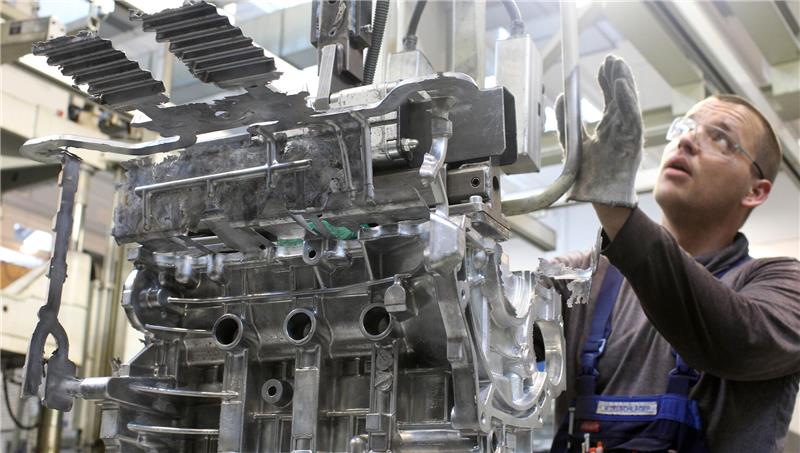 Ein Arbeiter ist an einem Motorblock beschäftigt.