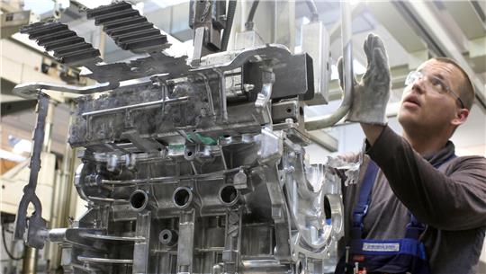 Ein Arbeiter ist an einem Motorblock beschäftigt.