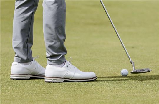 Ein Golfspieler puttet den Ball auf dem Grün.