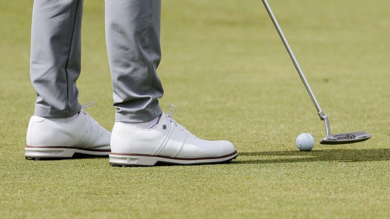 Ein Golfspieler puttet den Ball auf dem Grün.