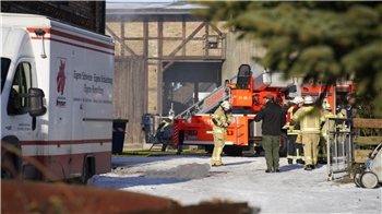 Mehrere Einsatzkräfte stehen vor der brennenden Scheune