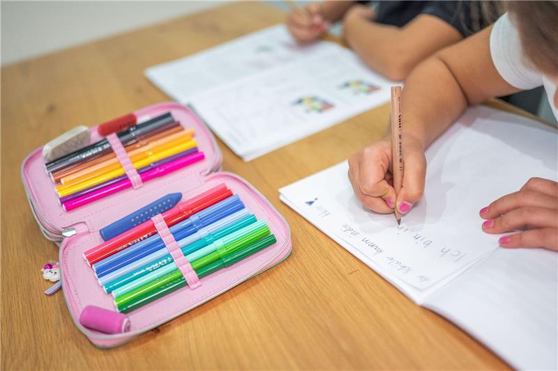 Untersuchungen zeigen Sprachprobleme vieler Kinder Ein Grundschüler und eine Grundschülerin sitzen in einem Wohnzimmer am Tisch und erledigen Schulaufgaben.