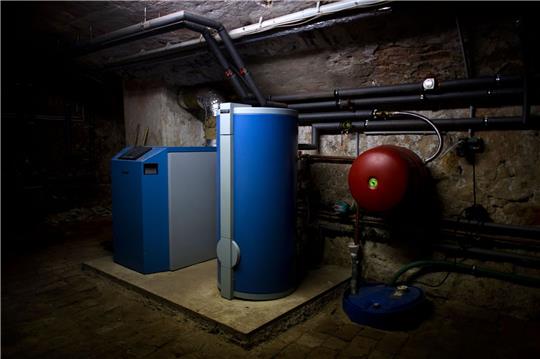 Ein Heizkessel und ein Warmwasserboiler stehen in einem Heizkeller in Dresden.