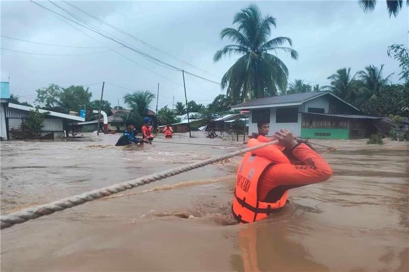 Mindestens 31 Tote durch Tropensturm auf den Philippinen Ein Helfer hält sich an einem Tau fest, während er durchs Wasser watet.