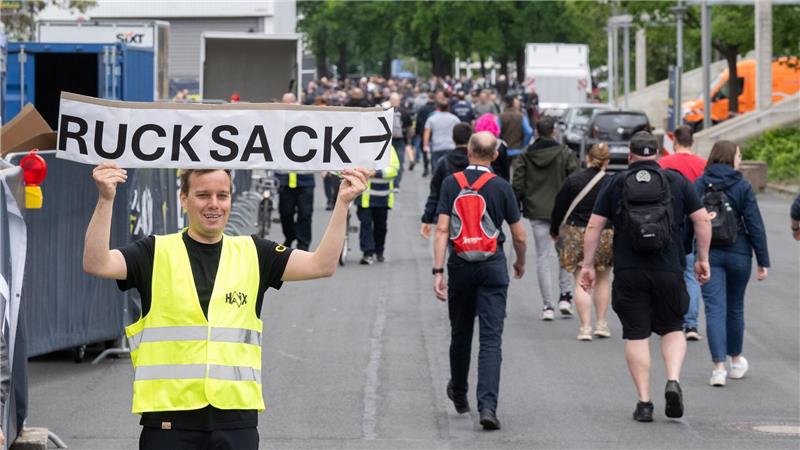 Ein Helfer weist mit einem Schild „Rucksack“ auf der Messe Interschutz den Weg zur Halle 15.