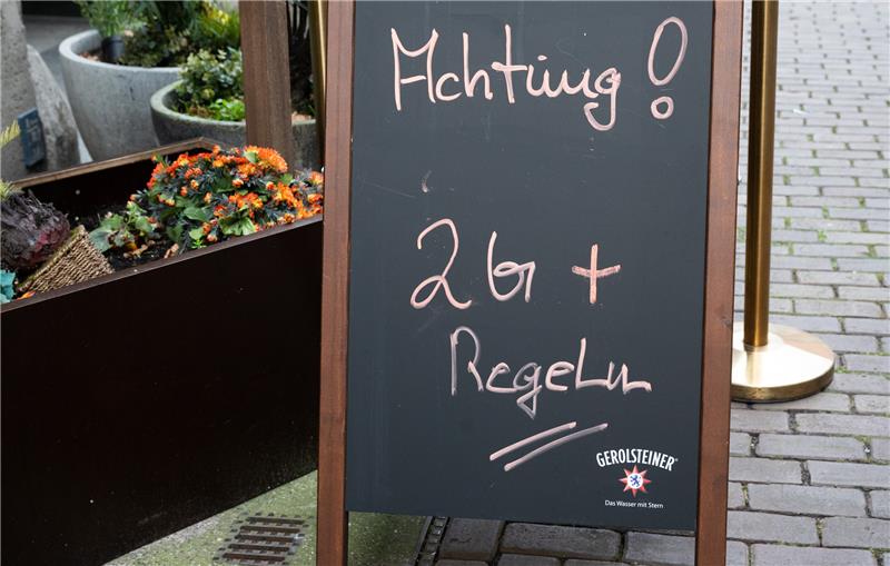 Ein Hinweisschild mit Aufschrift "Achtung! 2G+ Regel" steht vor einem Restaurant in der Innenstadt. Foto: Julian Stratenschulte/dpa/Illustration