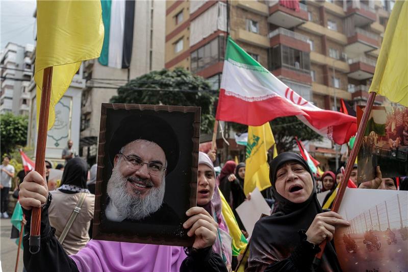 Nach langem Warten - Hisbollah-Chef Nasrallah hält Rede Ein Hisbollah-Anhänger hält ein Porträt von Hassan Nasrallah hoch: Der Hisbollah-Chef will sich zum ersten Mal seit Ausbruch des Gaza-Kriegs öffentlich äußern.
