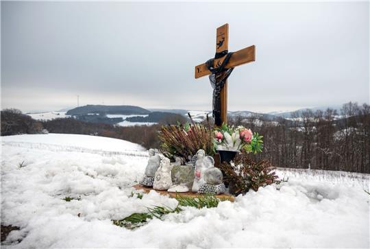Ein Holzkreuz, Engelsfiguren und Blumen erinnern bei Kusel an die zwei Polizisten, die vor einem Jahr im Dienst getötet wurden.