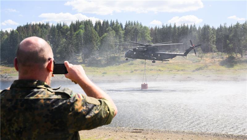 Waldbrand bei Schierke vorerst unter Kontrolle – Hubschrauber im Einsatz Ein Hubschrauber CH-53 der Bundeswehr entnimmt Wasser aus der Mandelholztalsperre zur Bekämpfung eines Waldbrandes bei Schierke. Foto: Julian Stratenschulte/DPA