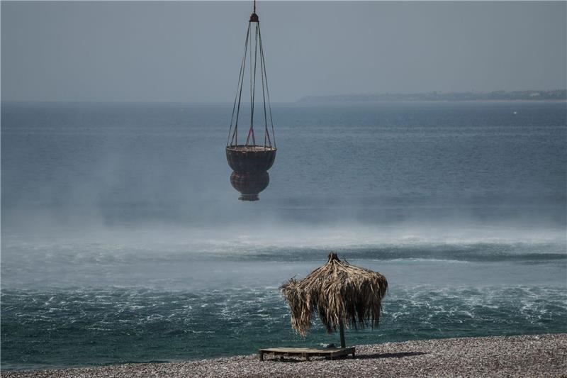 Griechische Feuerwehr: Brände größtenteils unter Kontrolle Ein Hubschrauber füllt während eines Waldbrandes in der Nähe des Dorfes Gennadi einen Korb mit Wasser aus dem Meer auf.