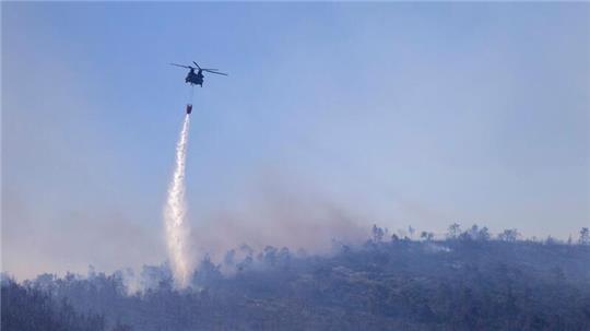 Ein Hubschrauber wirft Wasser auf einen Waldbrand im Norden Athens ab.
