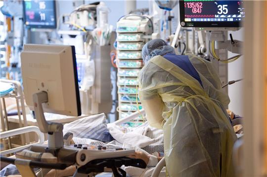 Ein Intensivpfleger steht auf der Intensivstation eines Krankenhauses neben einem Covid-19-Patienten.
